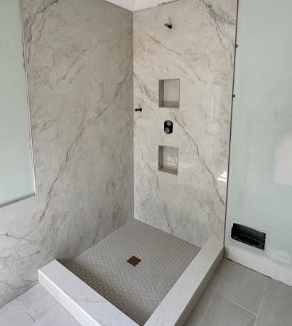Modern tiled shower with marble-look walls, recessed niches, and a square drain pan