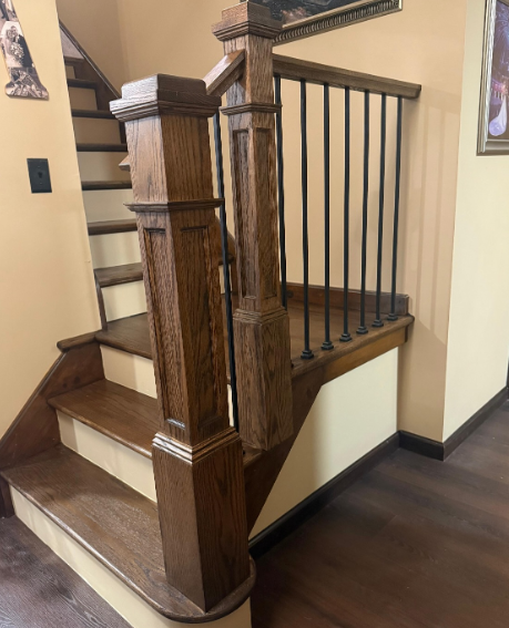 Wooden staircase with dark railing and cream walls in an indoor hallway