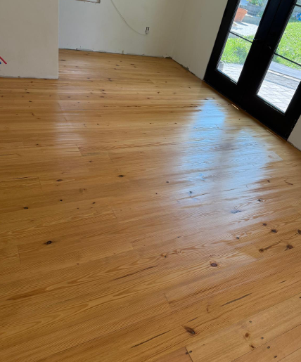 Empty room with light wood floor and glass doors opening to a balcony.