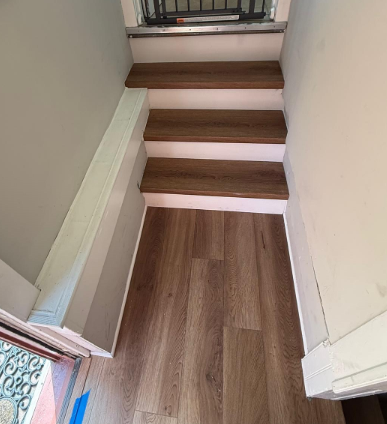 Narrow indoor staircase with wooden treads and white walls, viewed from the bottom.