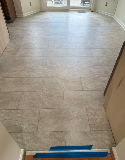 Empty room with light wood-look tile floor and a doorway leading to a bright windowed area