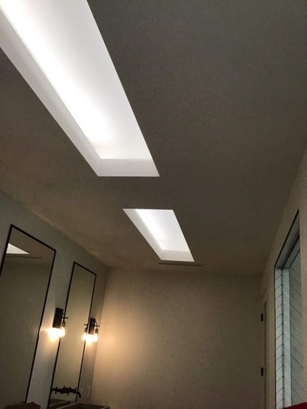 A room with two mirrors and a ceiling light