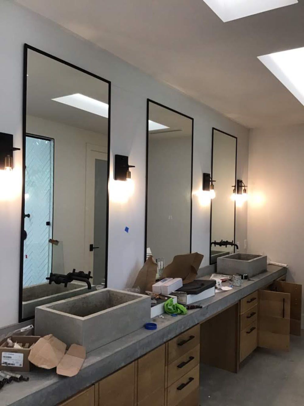 A well-lighted bathroom with three sinks and three mirrors