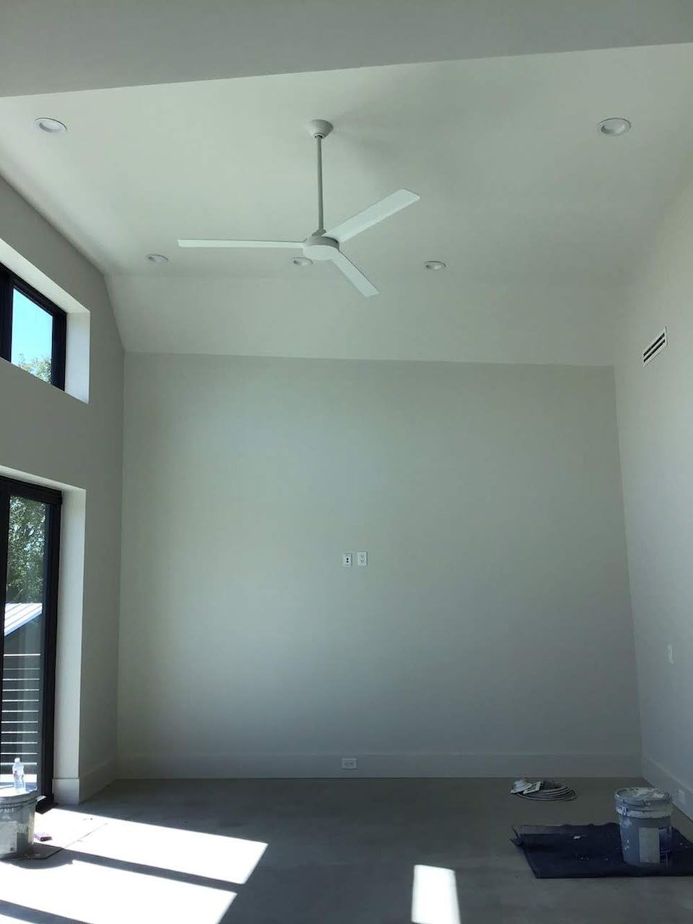 An empty room with a ceiling fan hanging from the ceiling