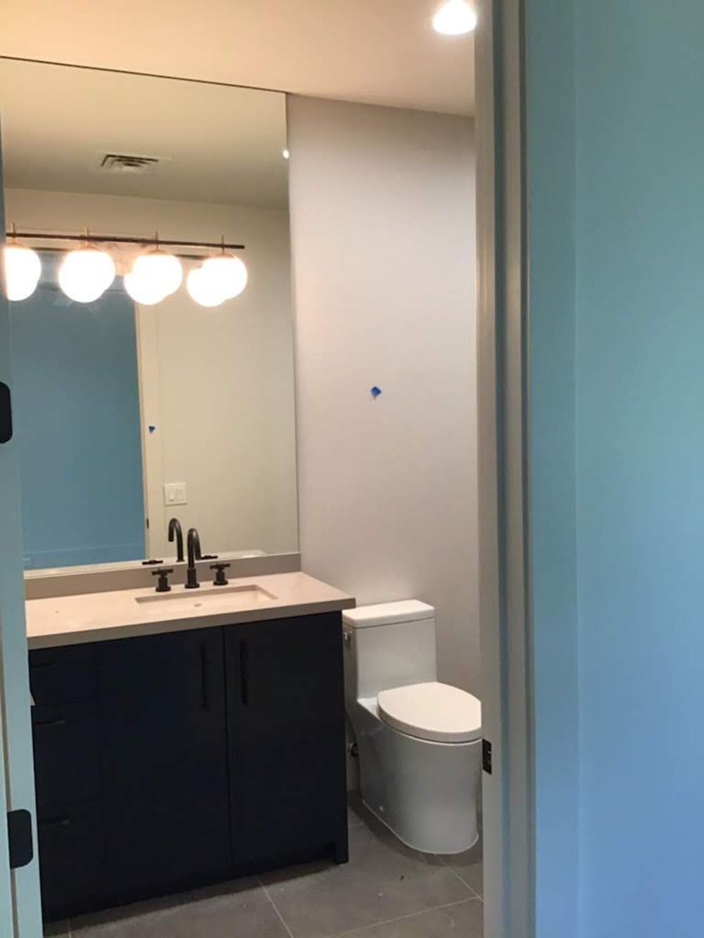 A bathroom with a toilet, sink, and mirror