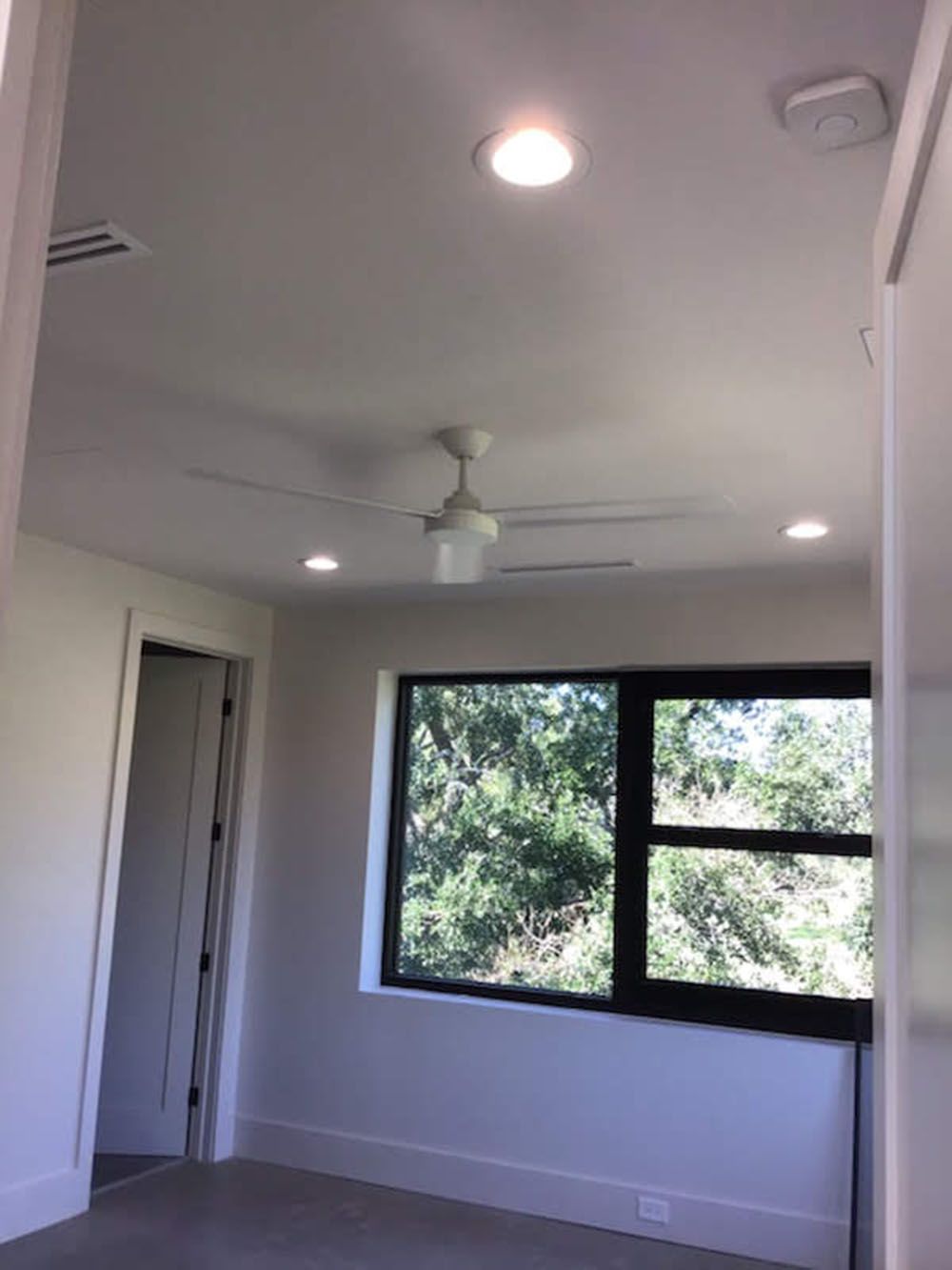 An empty room with a ceiling fan and a window