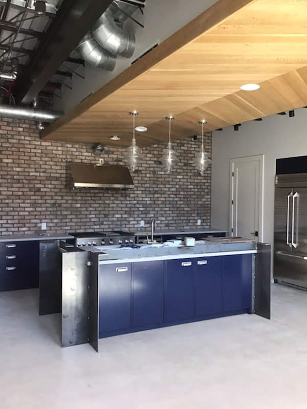 A kitchen with blue cabinets and a brick wall