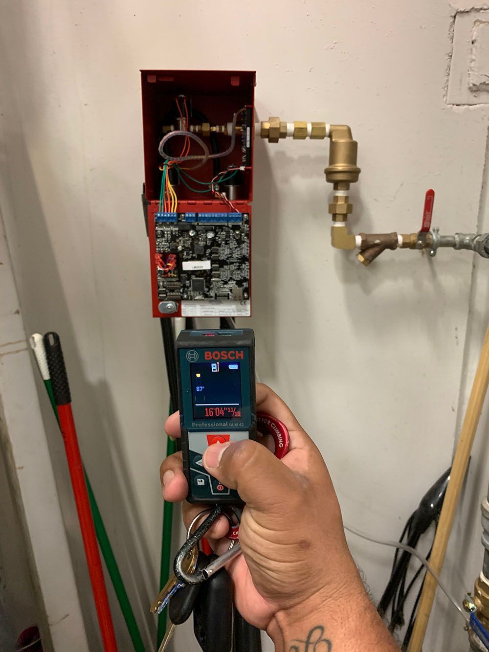 A person is holding a measuring device in front of a water heater