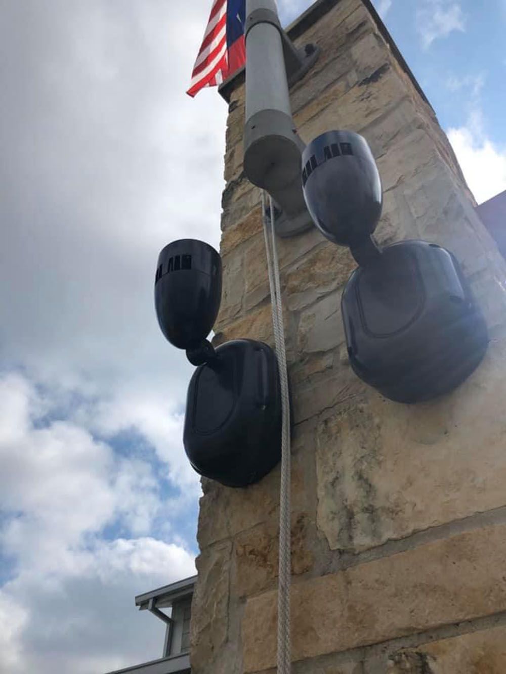 A brick post with a flag and lights attached to it