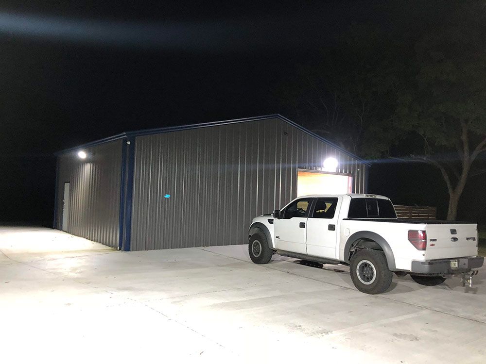 A white truck is parked in front of a well-lighted building at night