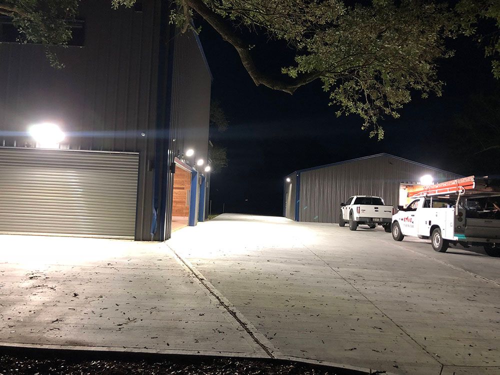 Two trucks are parked in front of a well-lighted building at night