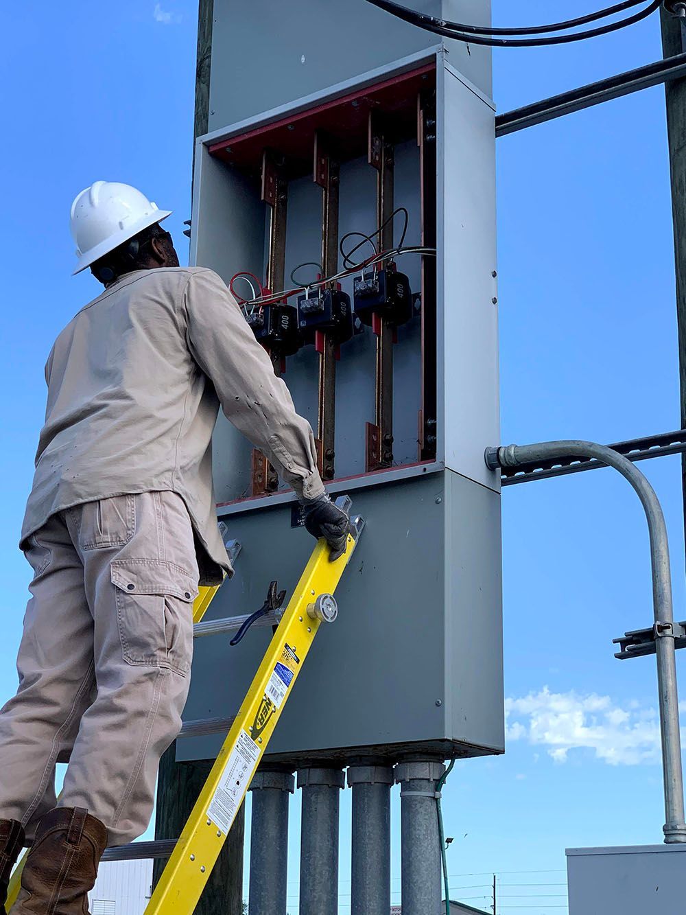 A man on a ladder working on an electrical box