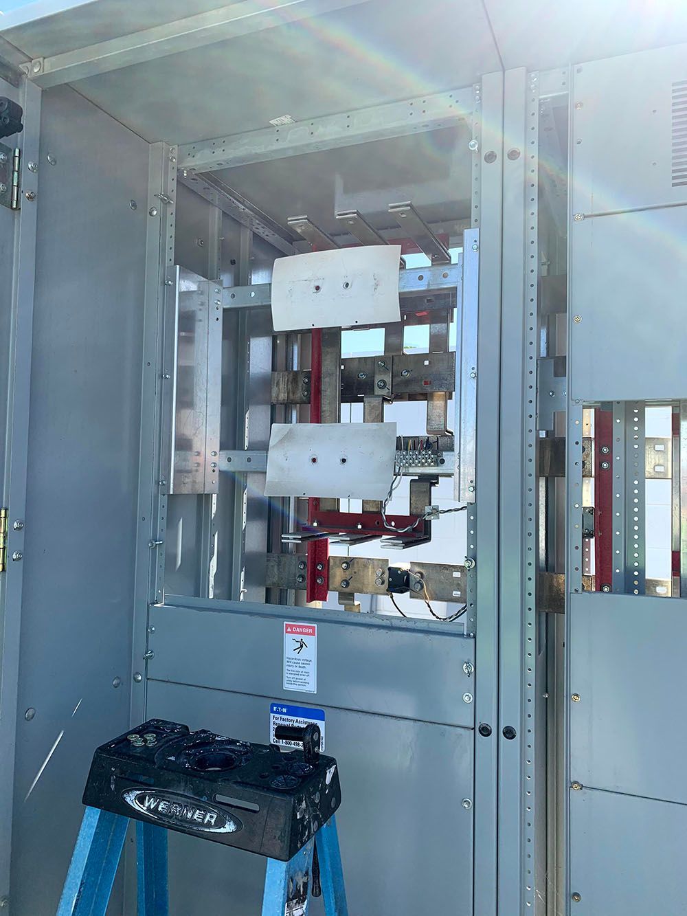 A blue ladder is sitting in front of a large electrical box