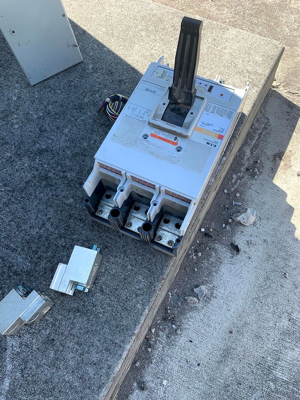 A broken electrical box is lying on the ground