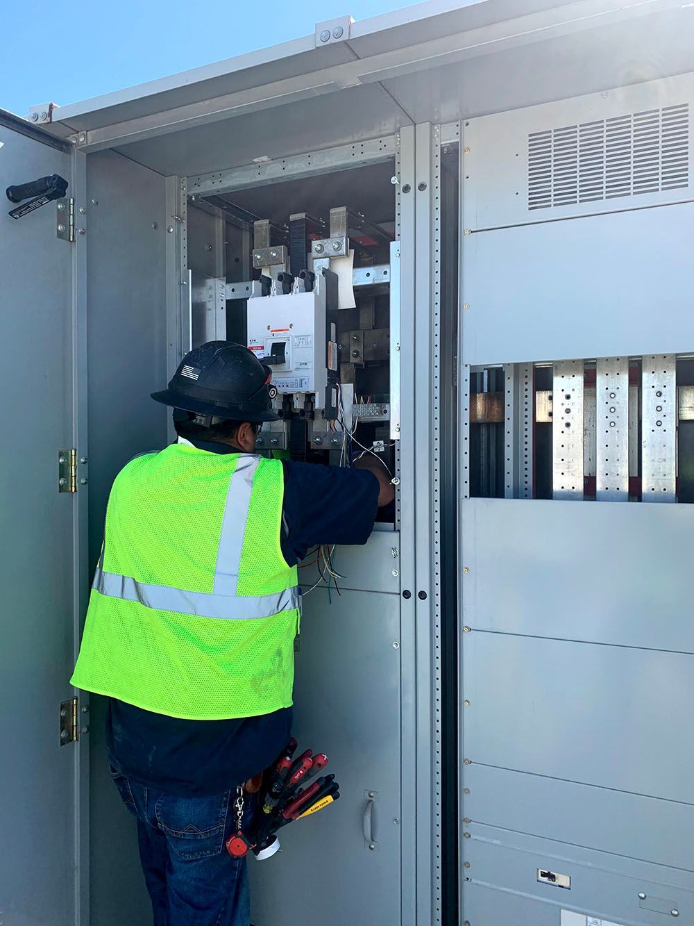 A man in a vest is working on an electrical box