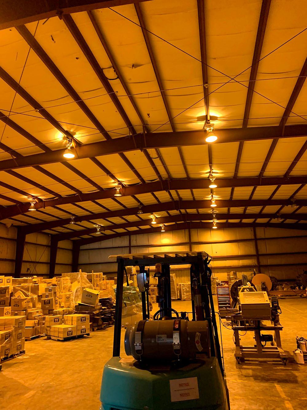 A forklift is parked in a large well-lighted warehouse