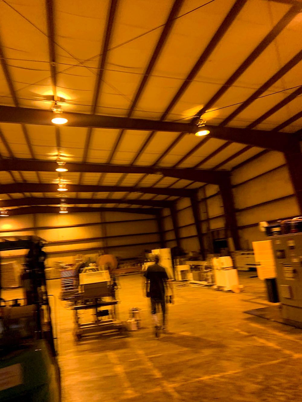 A man is walking through a large warehouse filled with lots of equipment