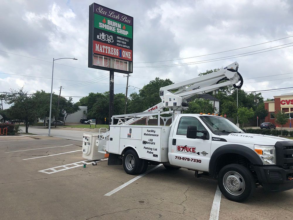 A white truck with a crane on top of it is parked beside a billboard