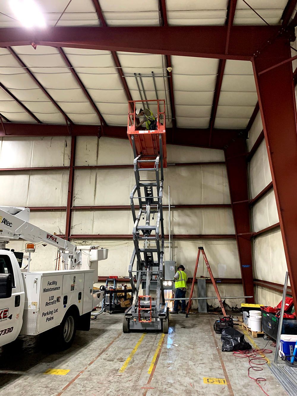 A man is standing on a scissor lift in a large building