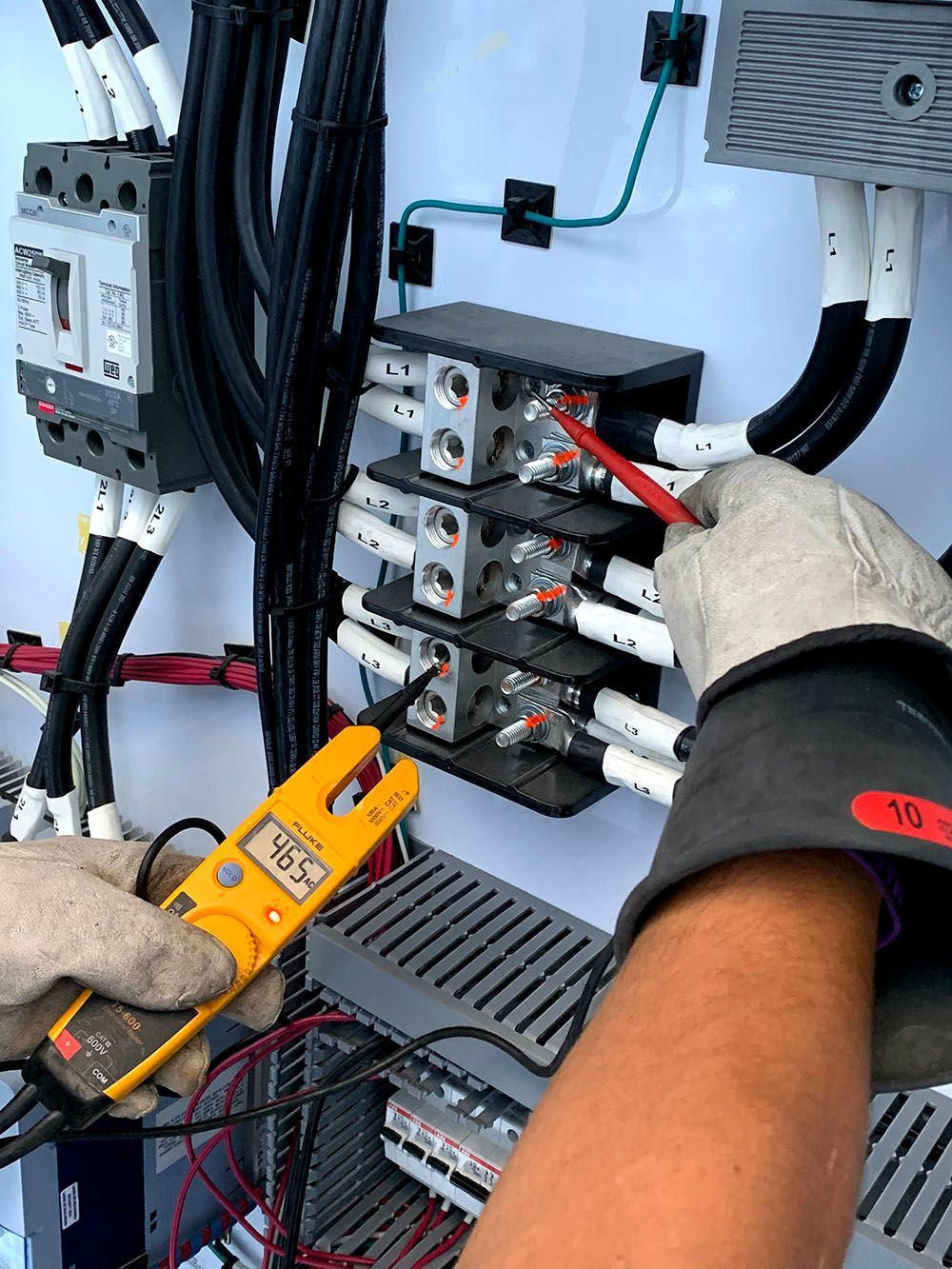 A person is using a clamp meter to test a circuit board