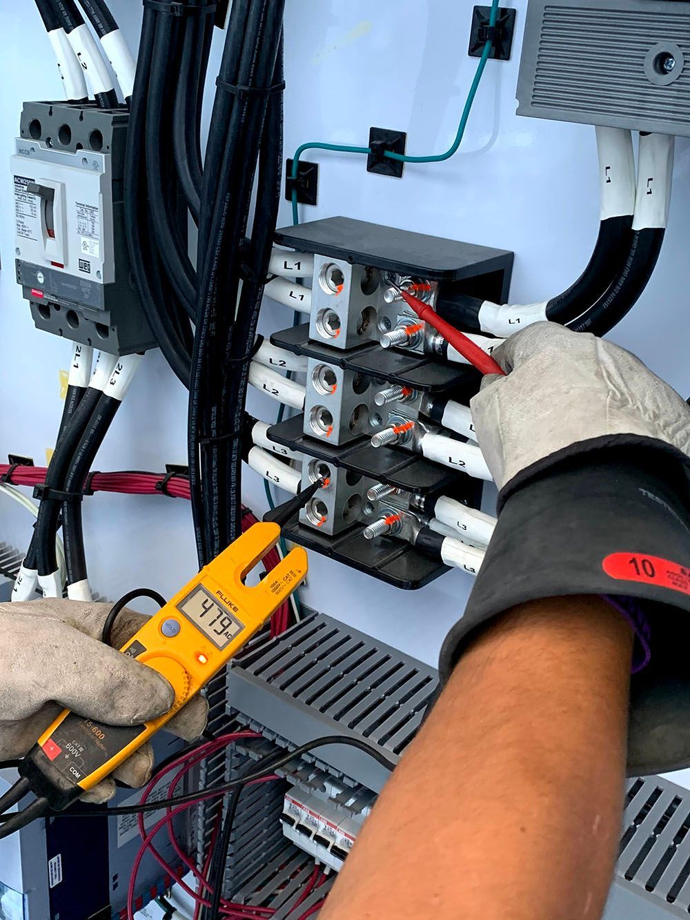 A man with a clamp meter testing a circuit board