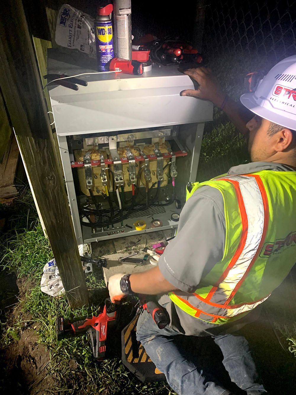 A man in a hard hat is working on an electrical box