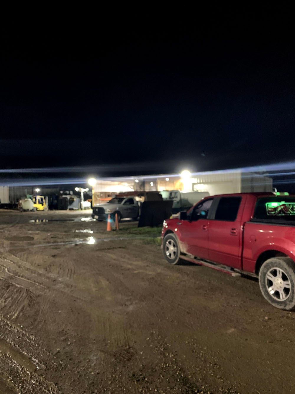 A red truck is parked in a well-lighted parking lot