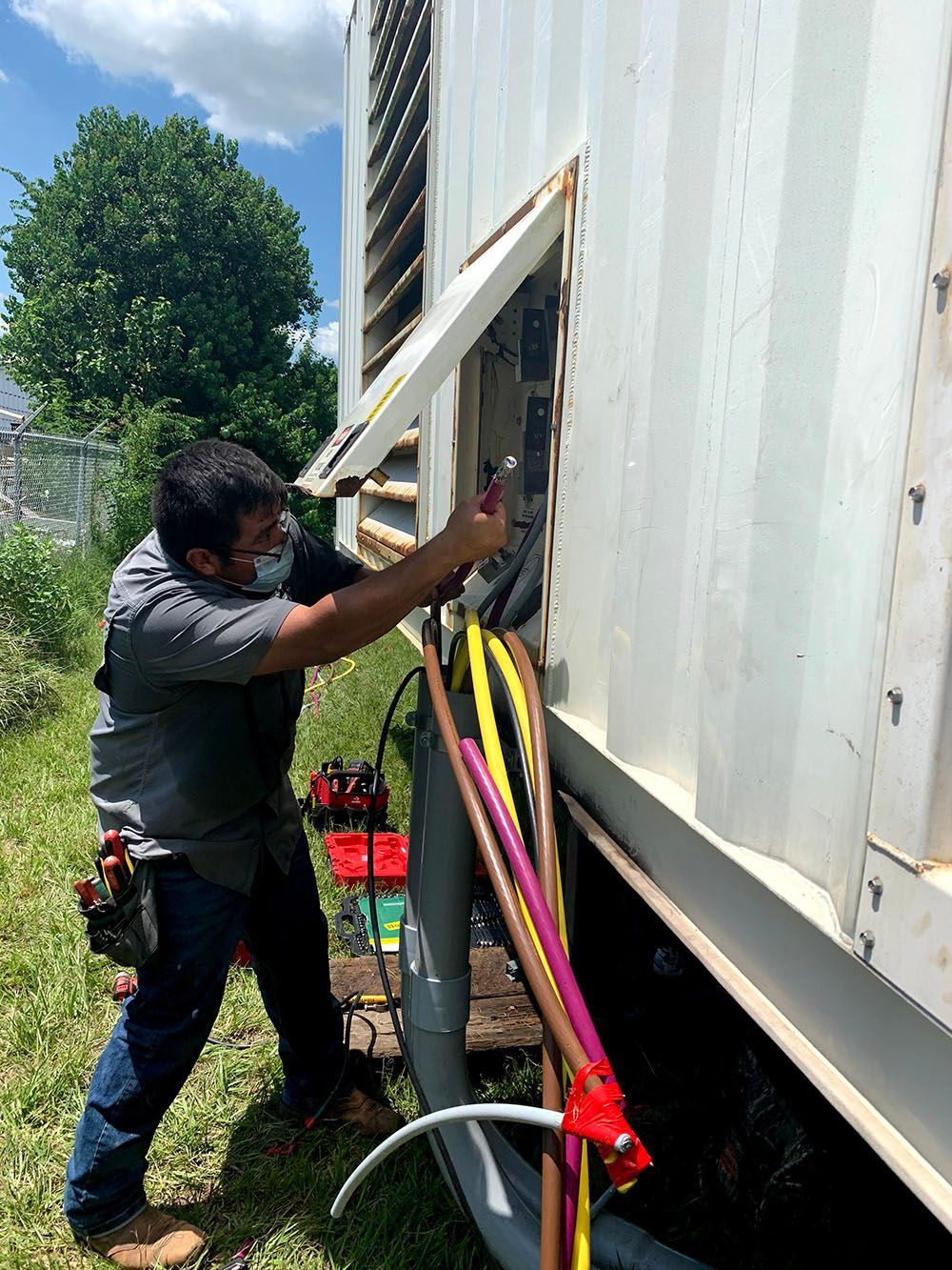 A man wearing a mask is working on a generator