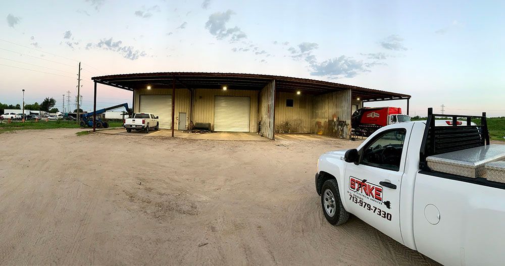 A white truck is parked in front of a well-lighted garage