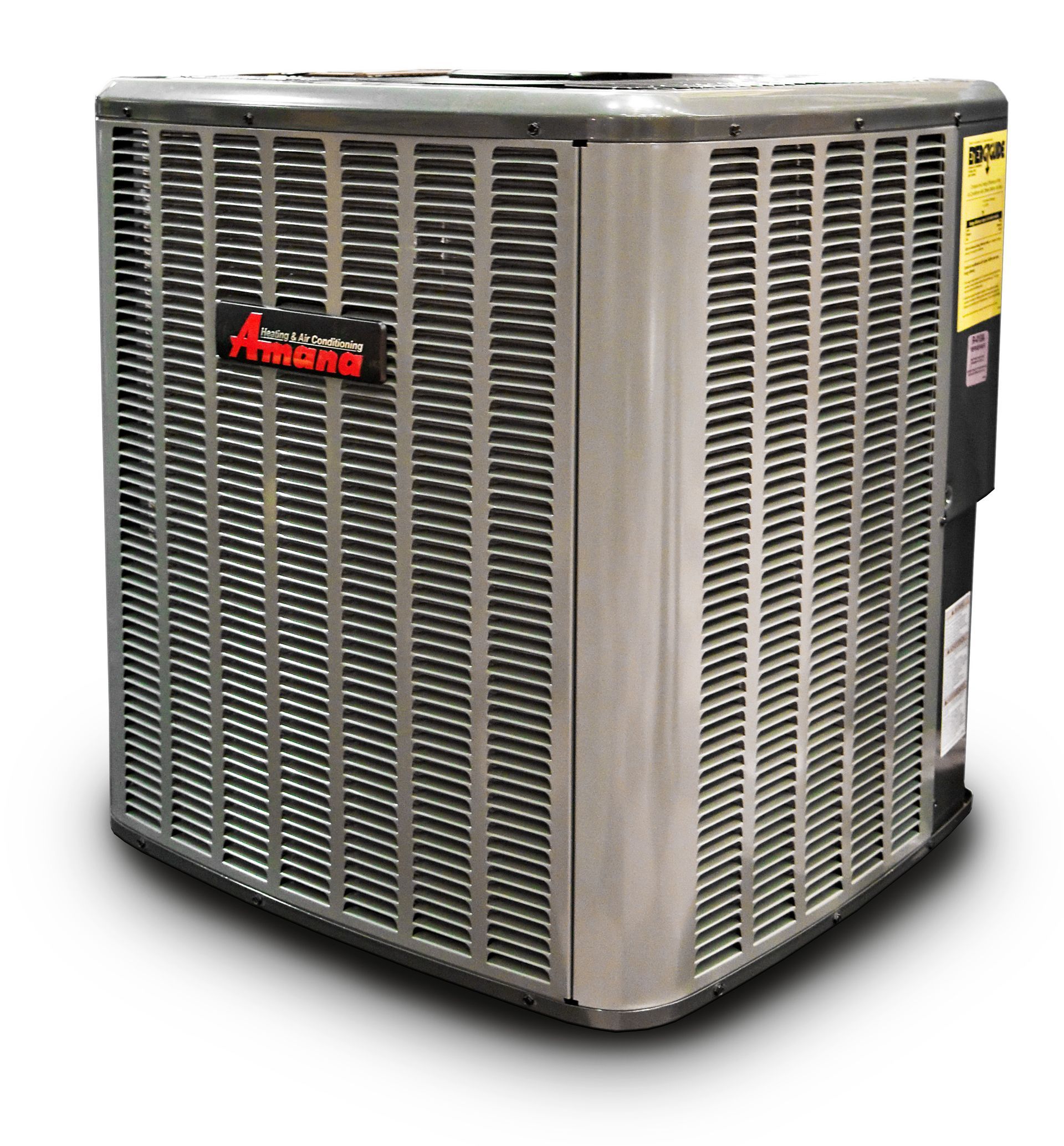 An Amana air conditioning unit, gray metal, with red logo, sitting outside.