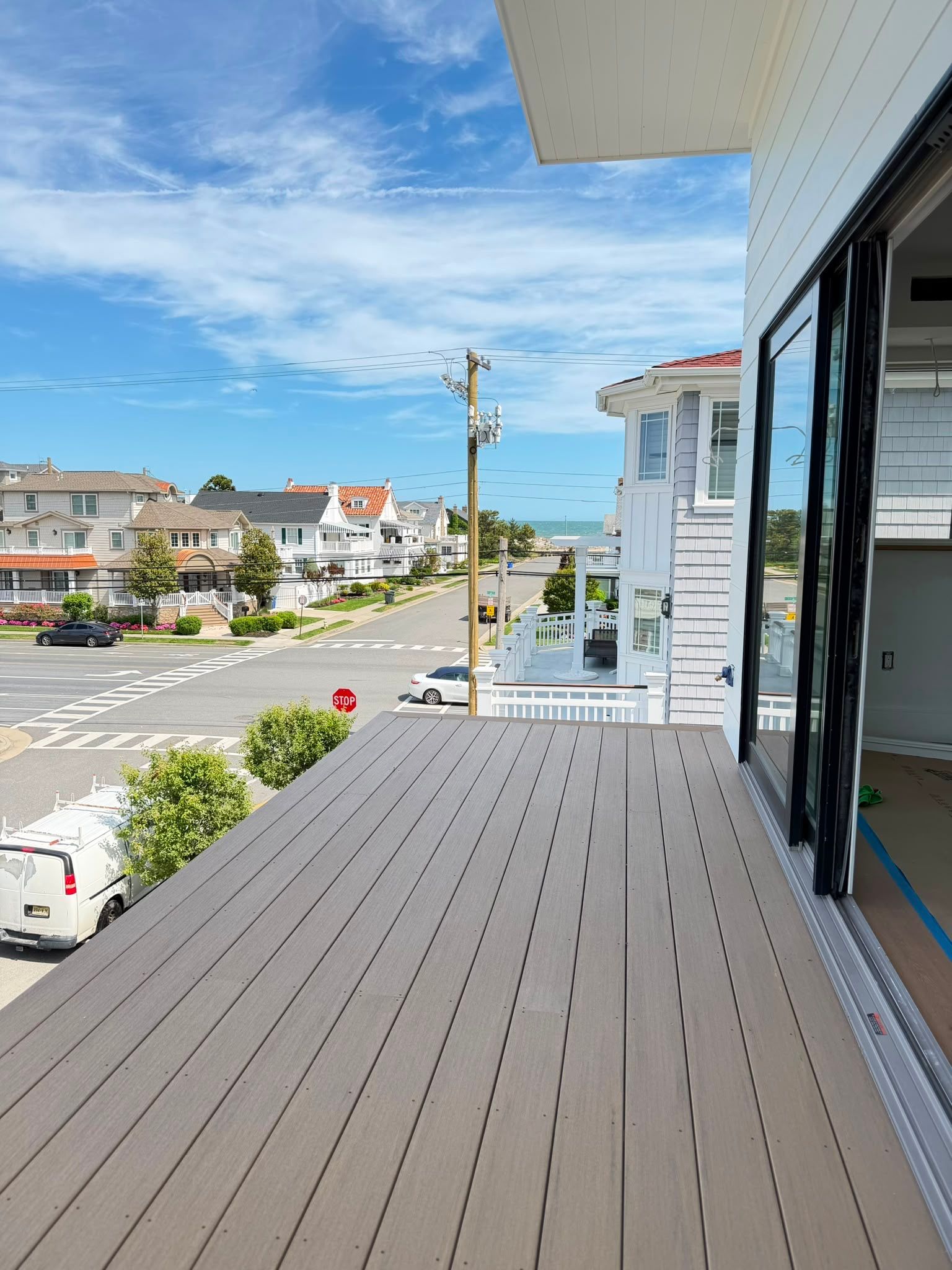 Balcony deck overlooking a quiet suburban street with white houses and blue sky