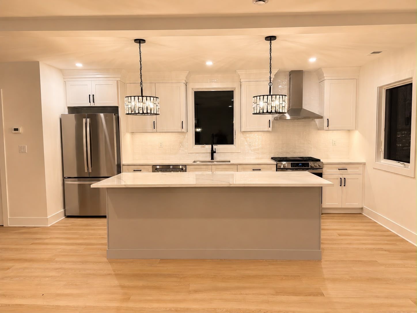 Bright modern kitchen with white cabinets, stainless steel appliances, and a large island with pendant lights