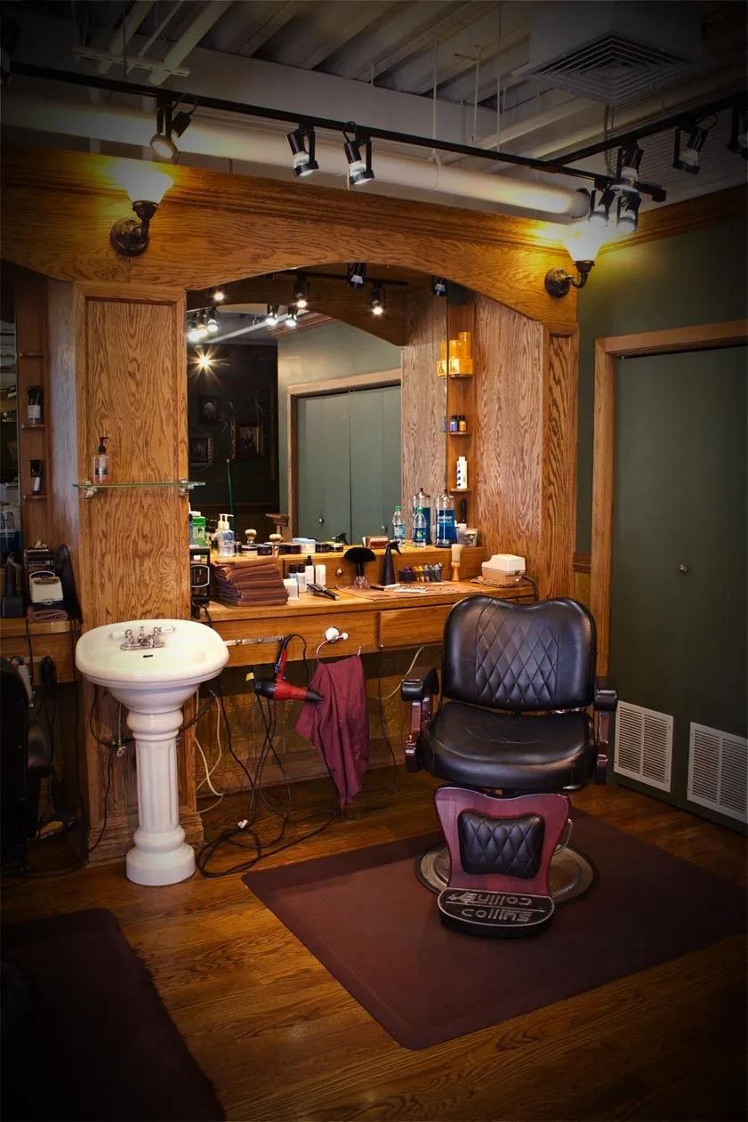 Barbershop interior with a barber chair, mirror, sink, and wood accents.