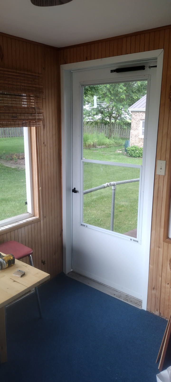 A screened in porch with a white door and a window.