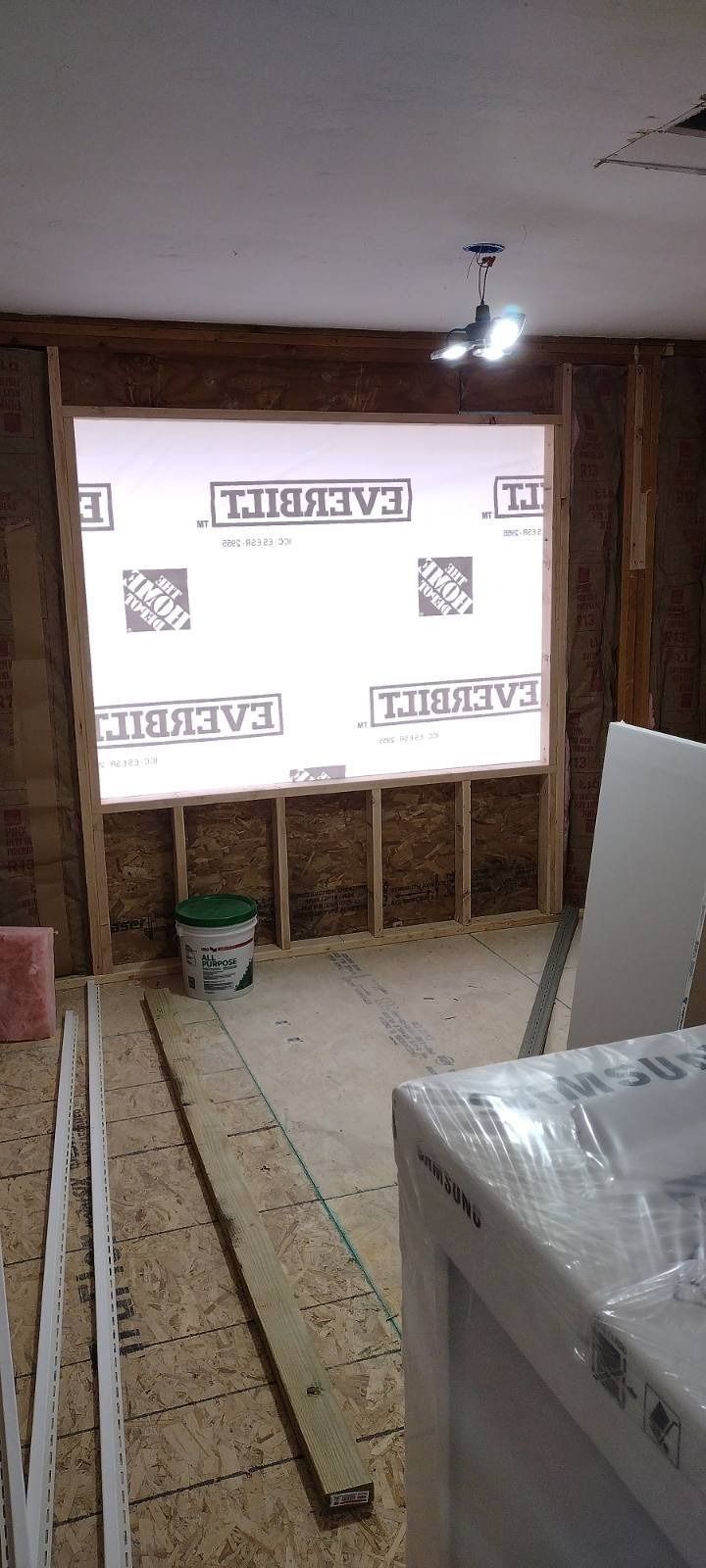 A room with a large window and a bucket on the floor.