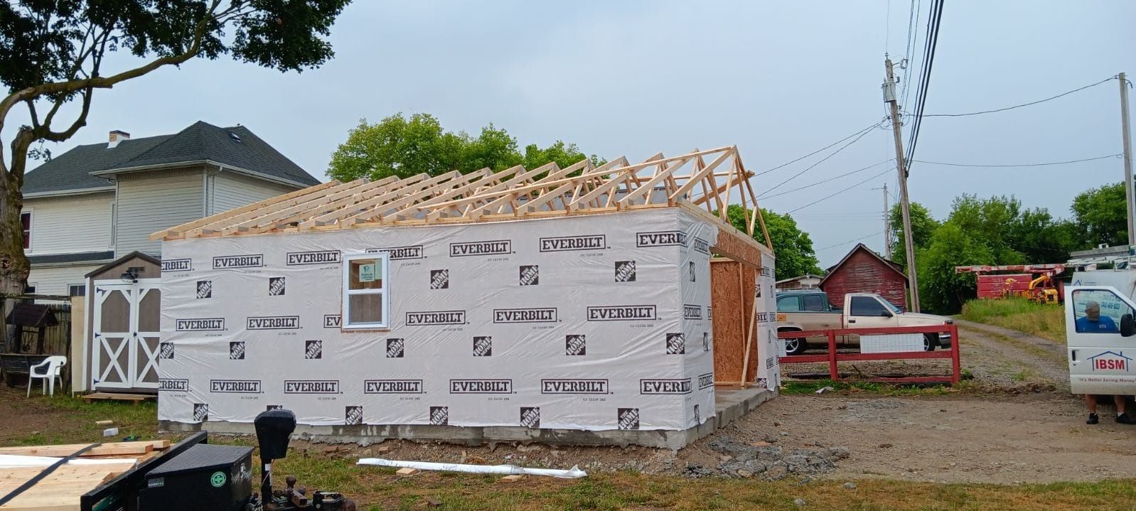 A building is being built in a yard with a truck parked in front of it.