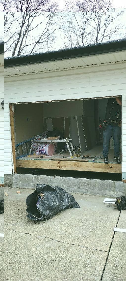 A man is standing in front of a garage door that is being opened.
