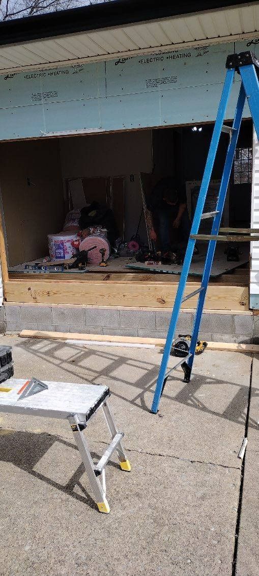A blue ladder is sitting in front of a garage door.