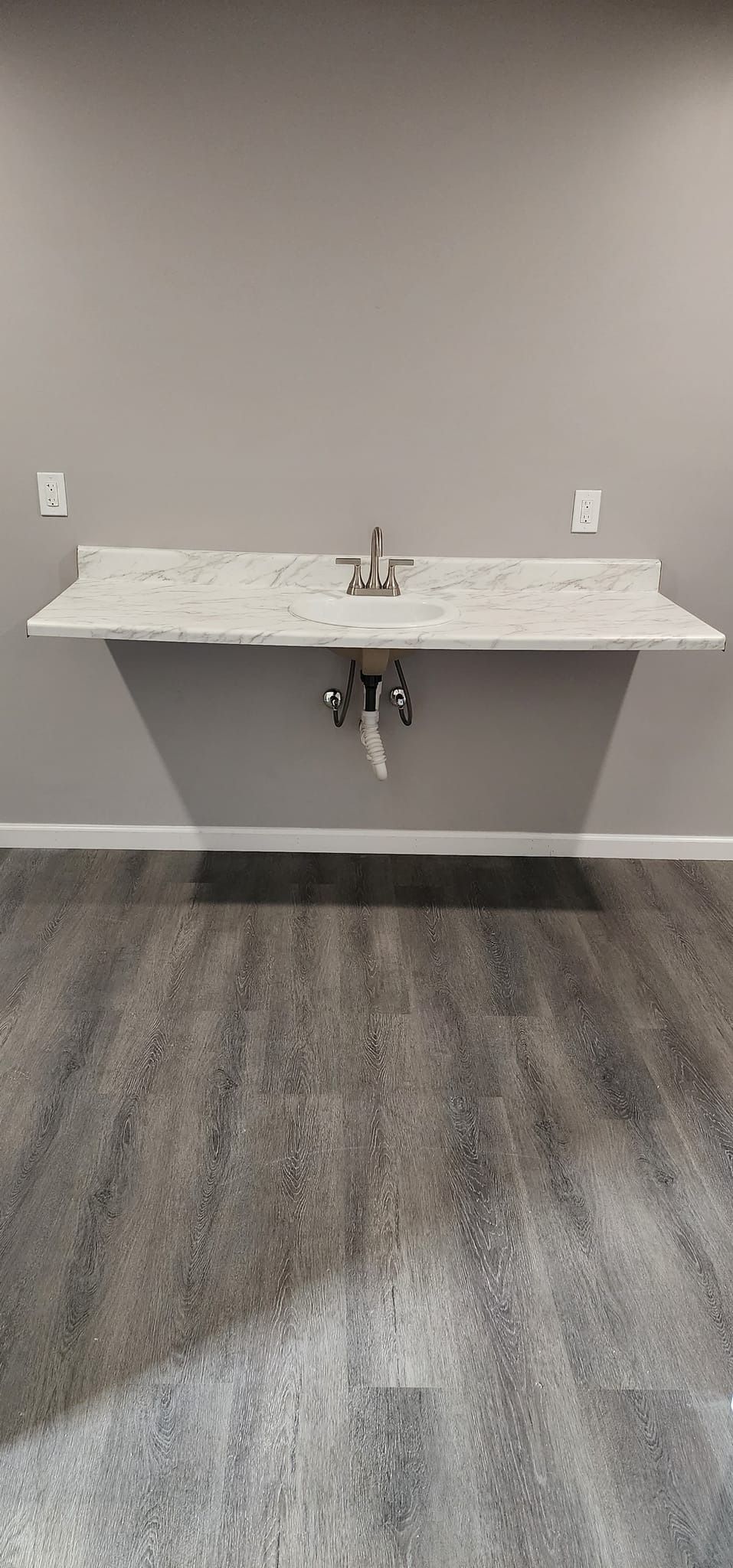 A bathroom with a sink and a wooden floor.