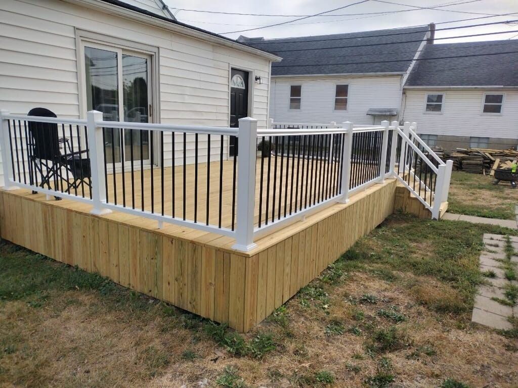 A wooden deck with a white railing in front of a house.