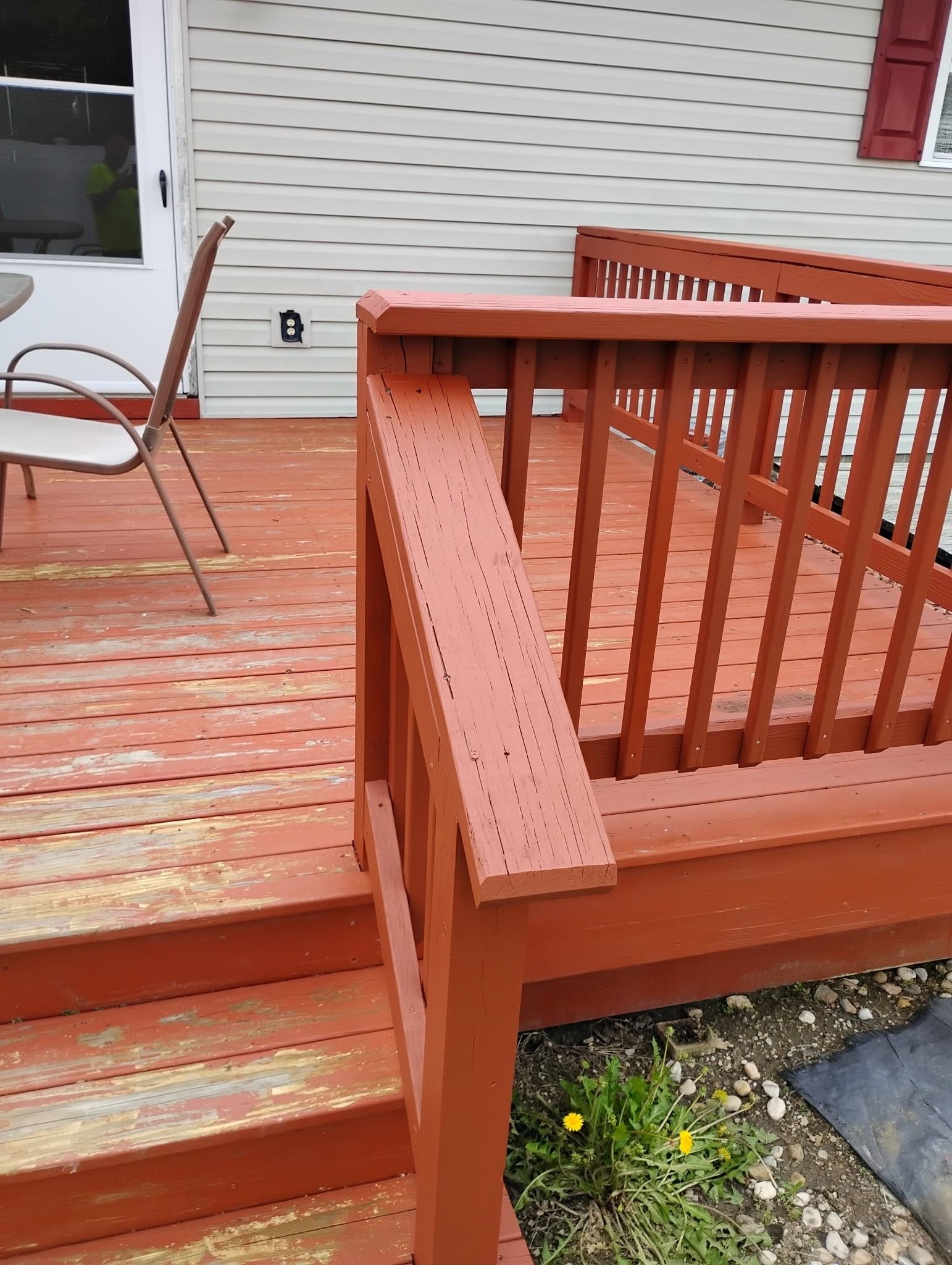 A red wooden deck with stairs leading up to it.