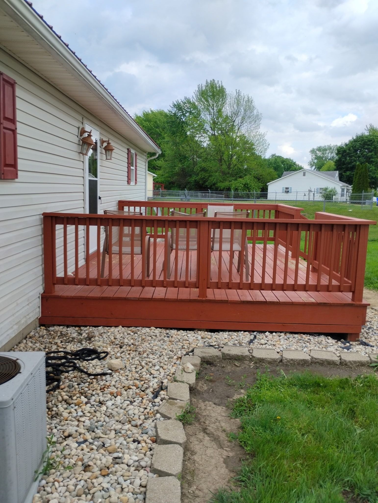 A red deck is sitting in front of a white house.
