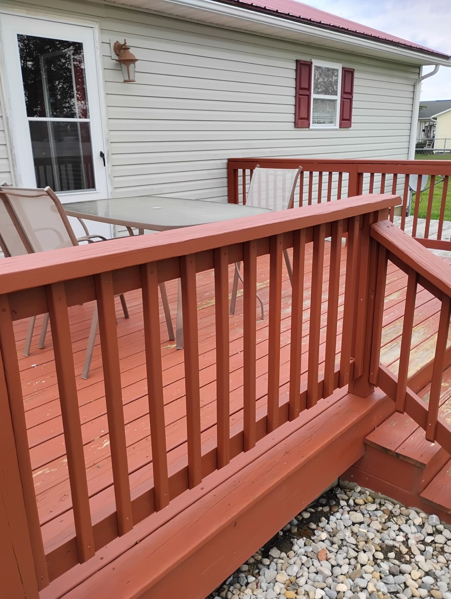 A red deck with a white house in the background