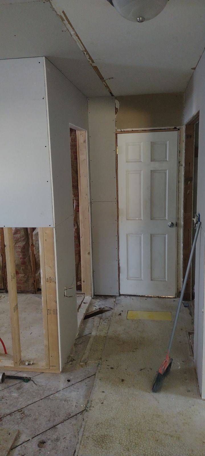 A hallway with a door and a broom in it.