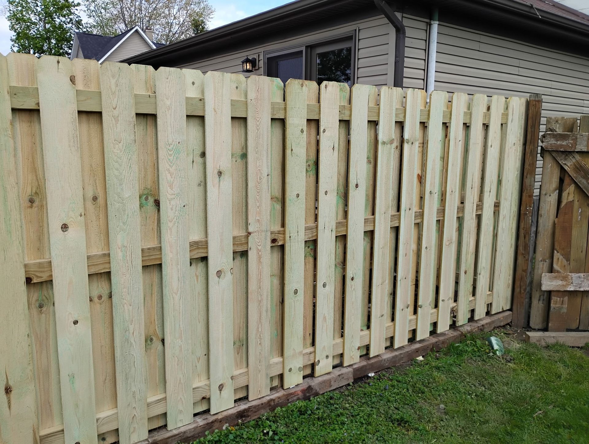 A wooden fence is sitting in front of a house.