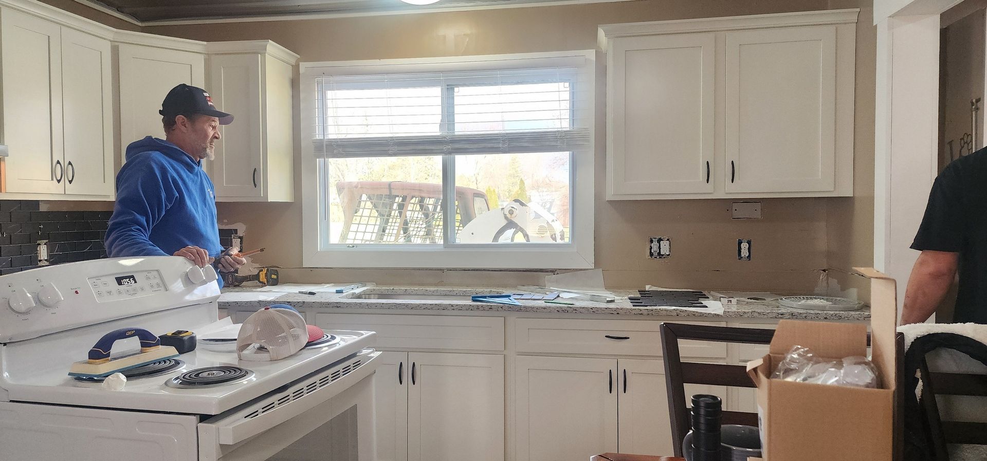 A man is standing in a kitchen next to a stove.