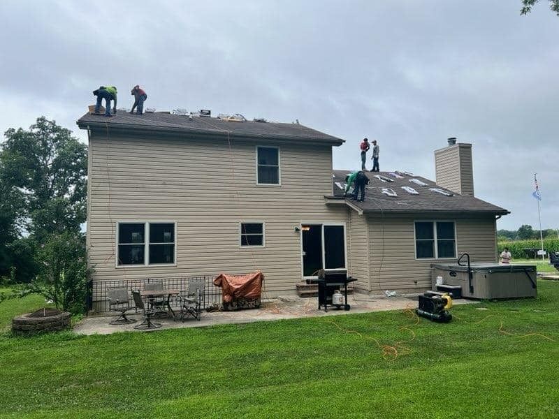 A group of people are working on the roof of a house.