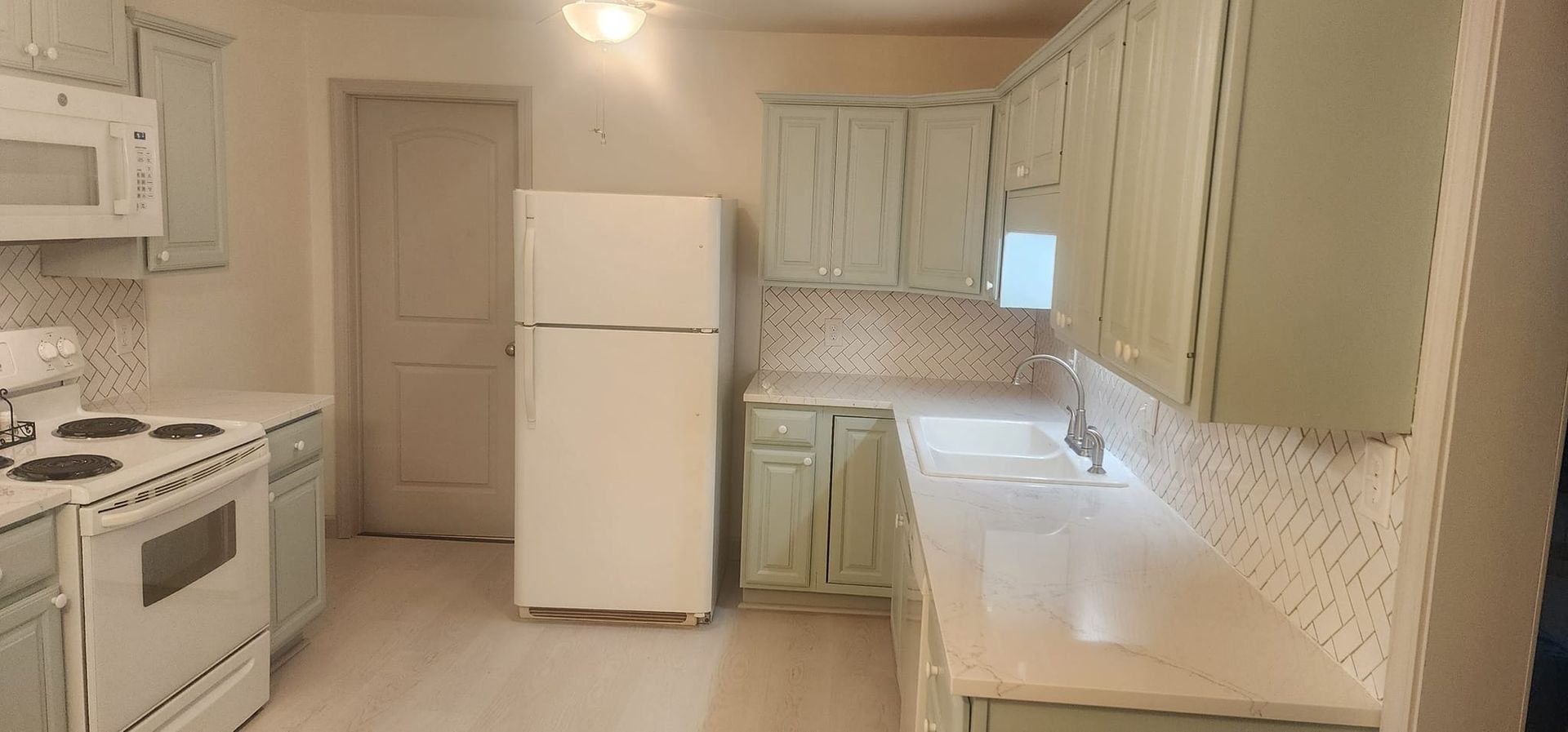 A kitchen with a refrigerator , stove , microwave and sink.