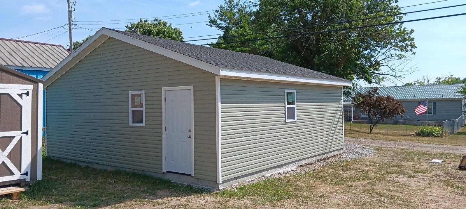 A small shed is sitting in the middle of a grassy field.