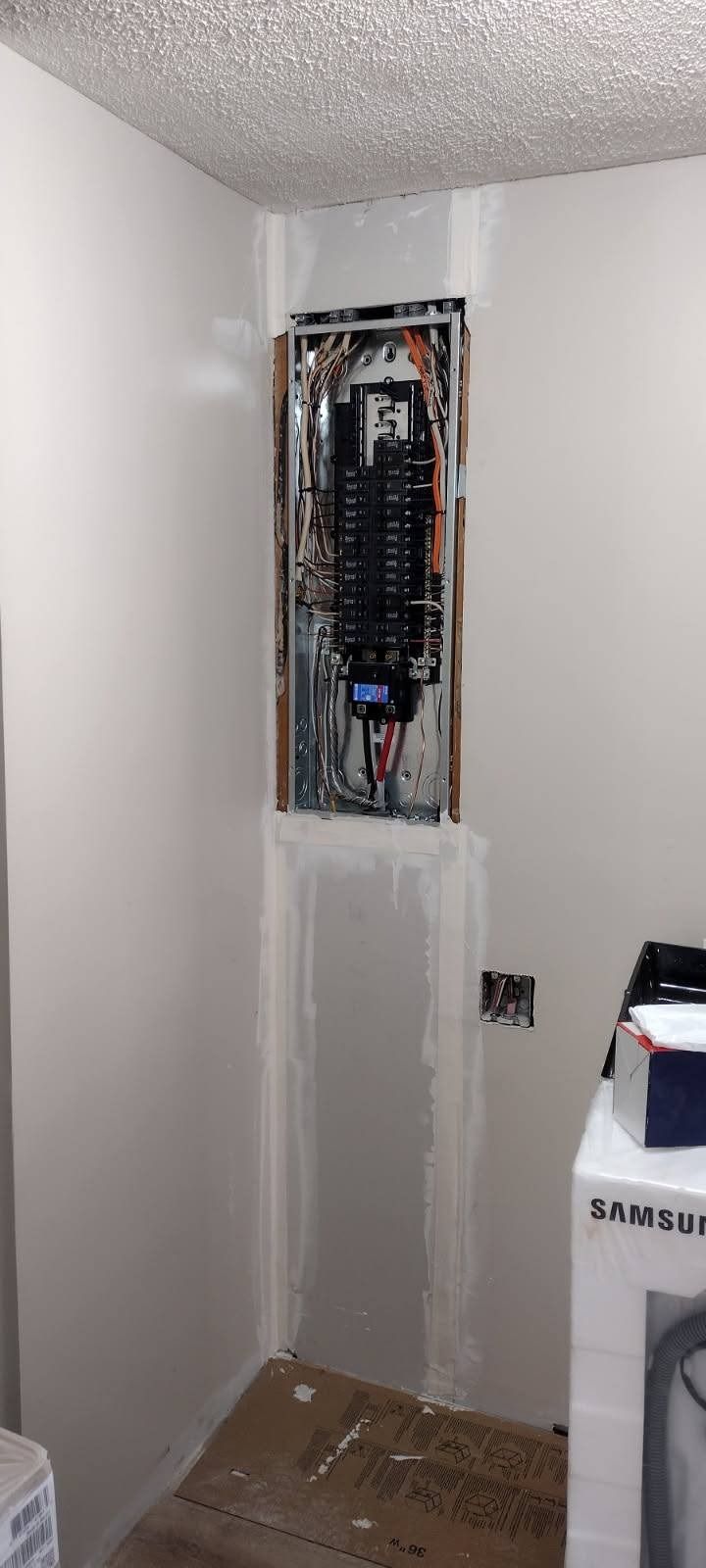 A laundry room with a washer and dryer and a electrical box on the wall.